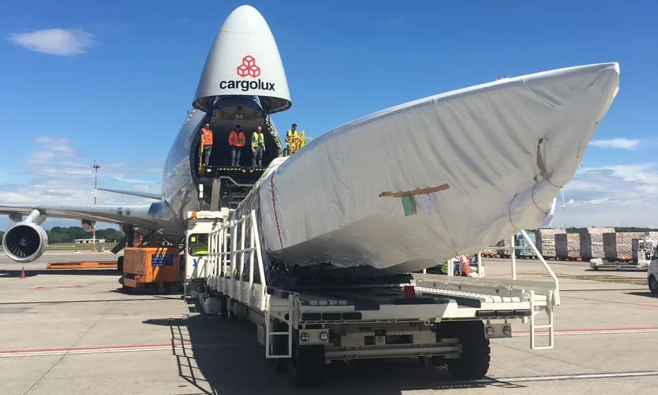 Boat on a transporter lined up in front of the open nose door of a 747 freighter