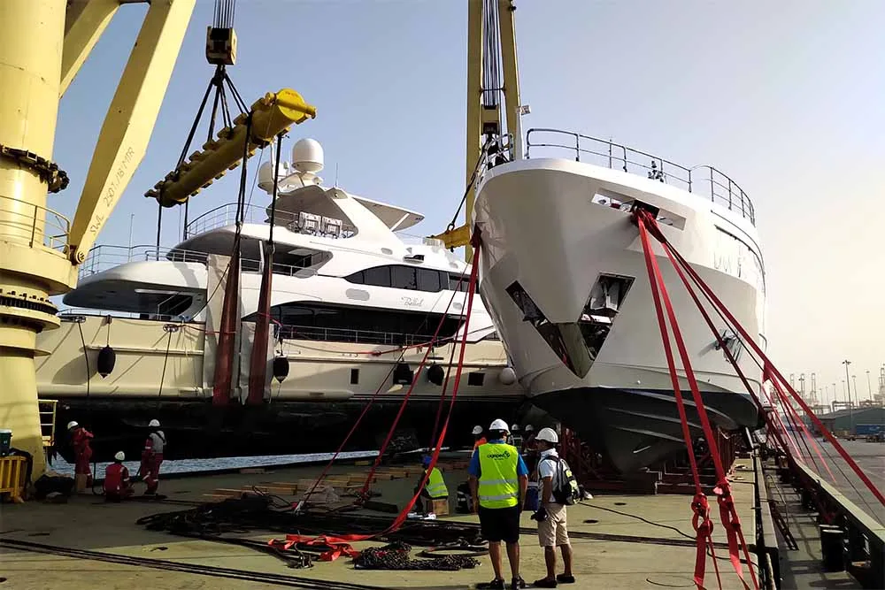 Two motor yachts on deck, lashed down with red straps over their cradles
