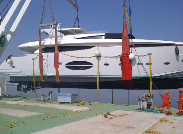 Motor yacht in slings above the quay of a Dubai port terminal