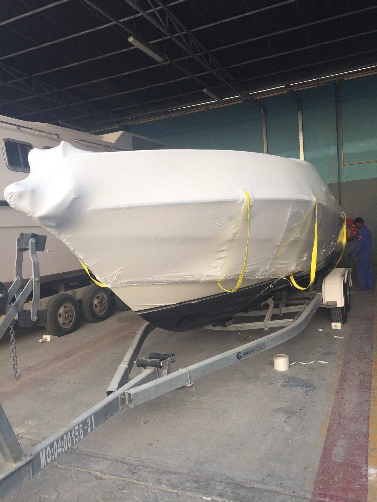 Shrink-wrapped yacht on a lowbed trailer for road transport to Bahrain