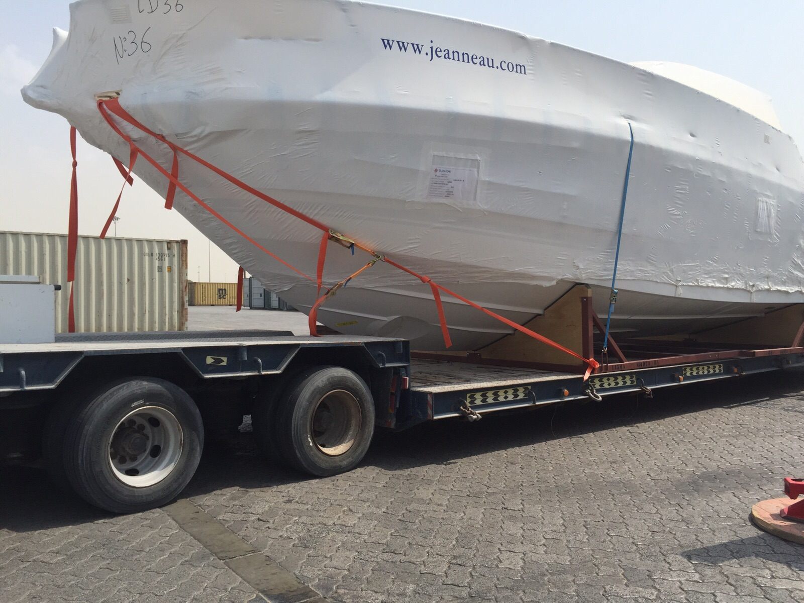 Shrink-wrapped motor yacht on a lowbed trailer for road transport from Dubai to Oman