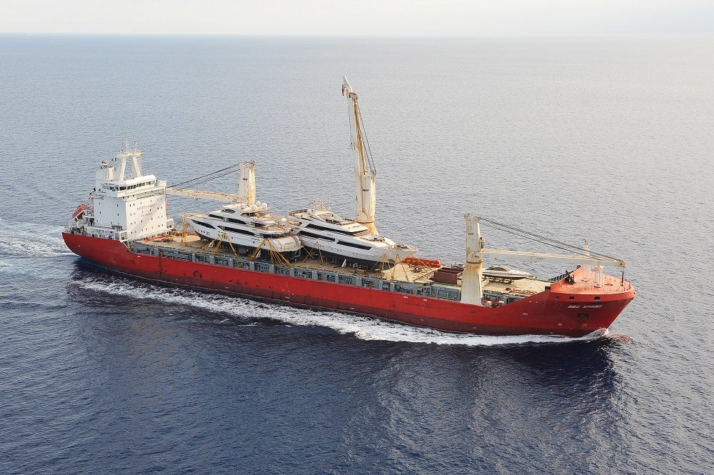Cargo ship at sea carrying yachts on deck on the route between Dubai and Singapore