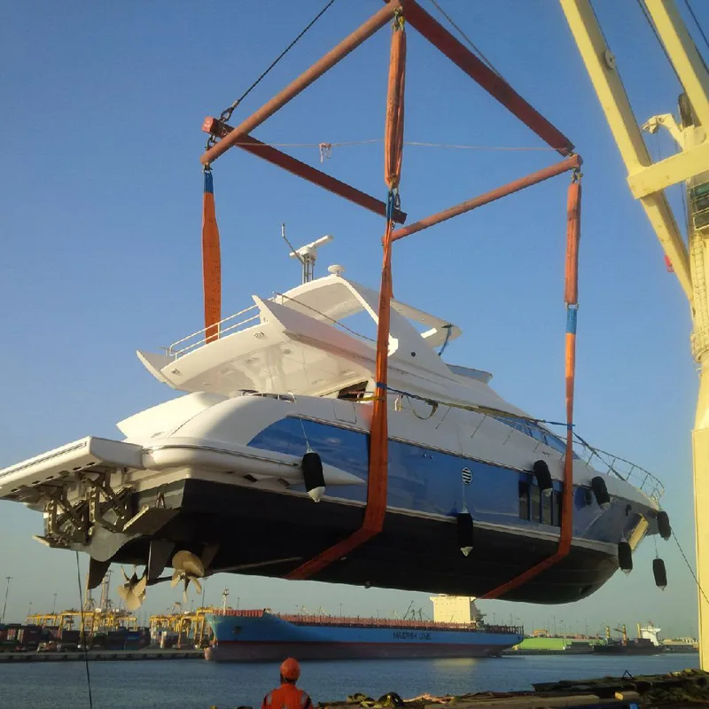 Motor yacht lifted in slings with a spreader frame by a ship's crane