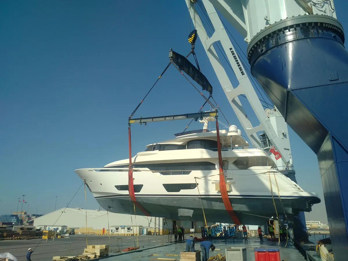 Motor yacht in slings beside the ship, about to be loaded