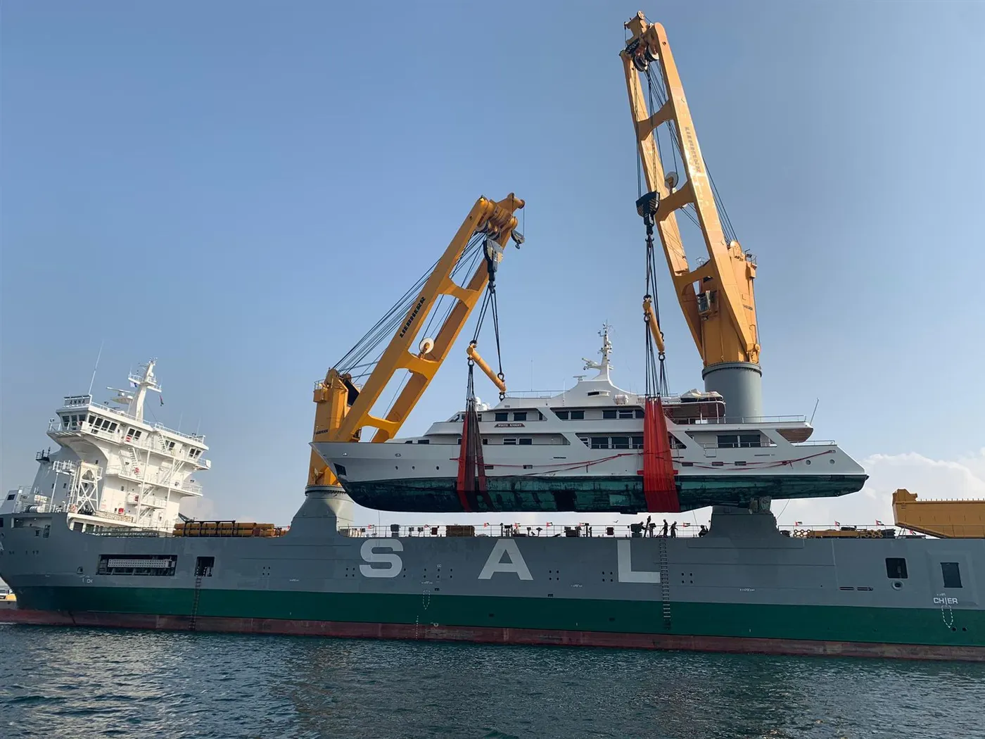 Heavy lift ship lifting a load with two of its own cranes working in tandem