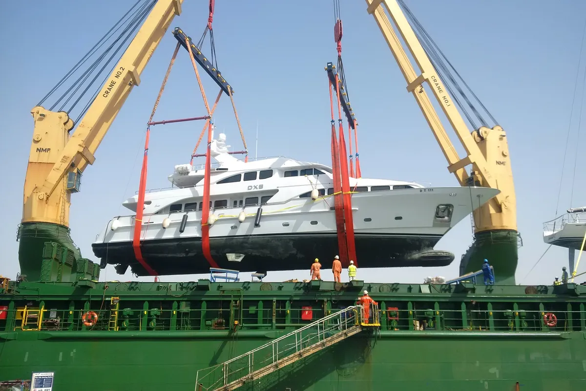 Motor yacht lifted in slings between two ship cranes for lift on lift off transport