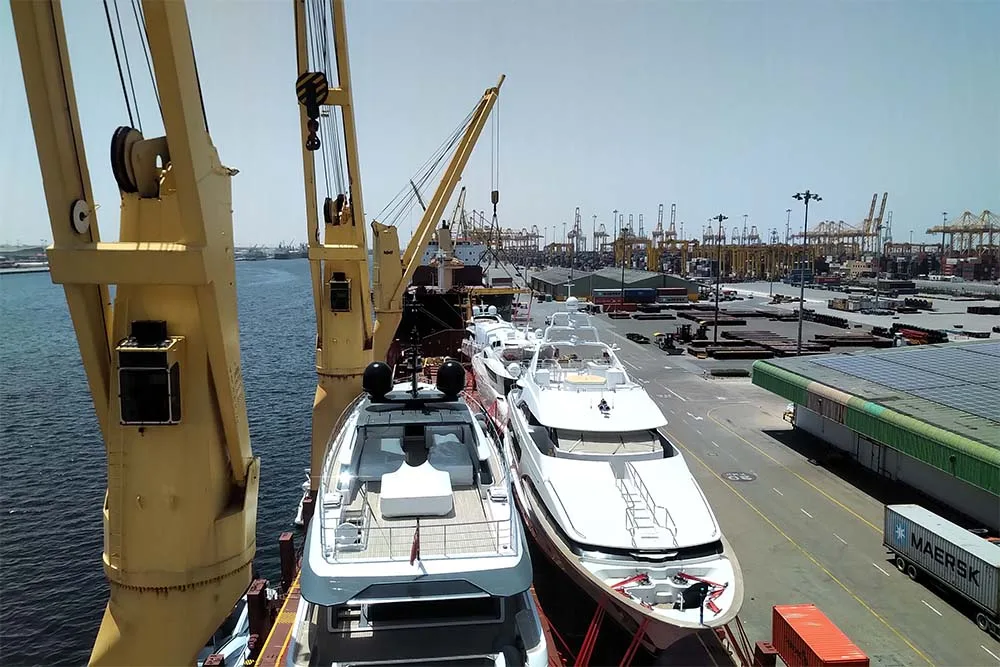 Two motor yachts lashed side by side on a ship's deck, seen from above at the quay