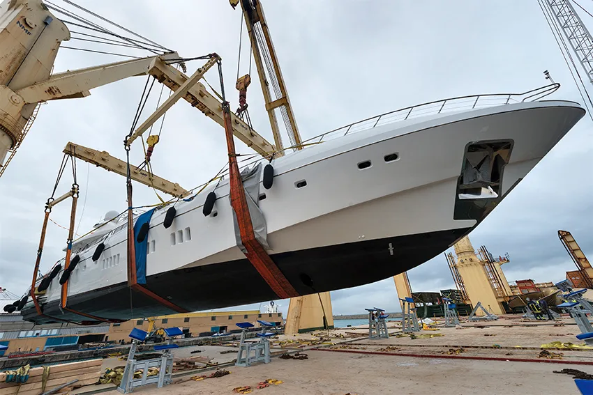 Mega yacht lifted in slings by two ship cranes during loading