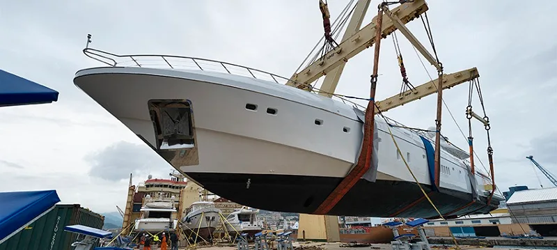 Motor yacht lifted by the cranes of a heavy lift ship